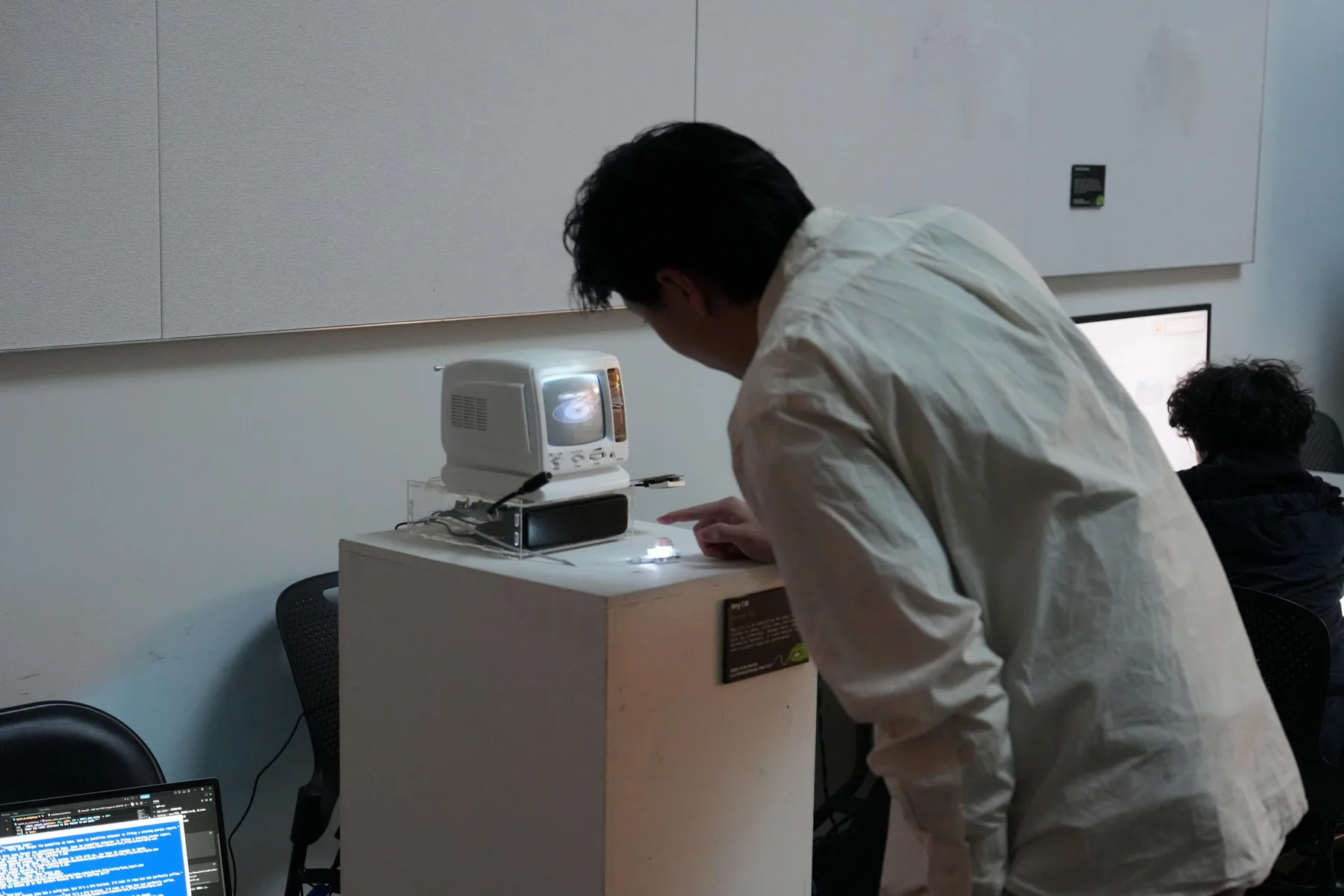 A visitor leaning toward the physical joke robot and its illuminated input button