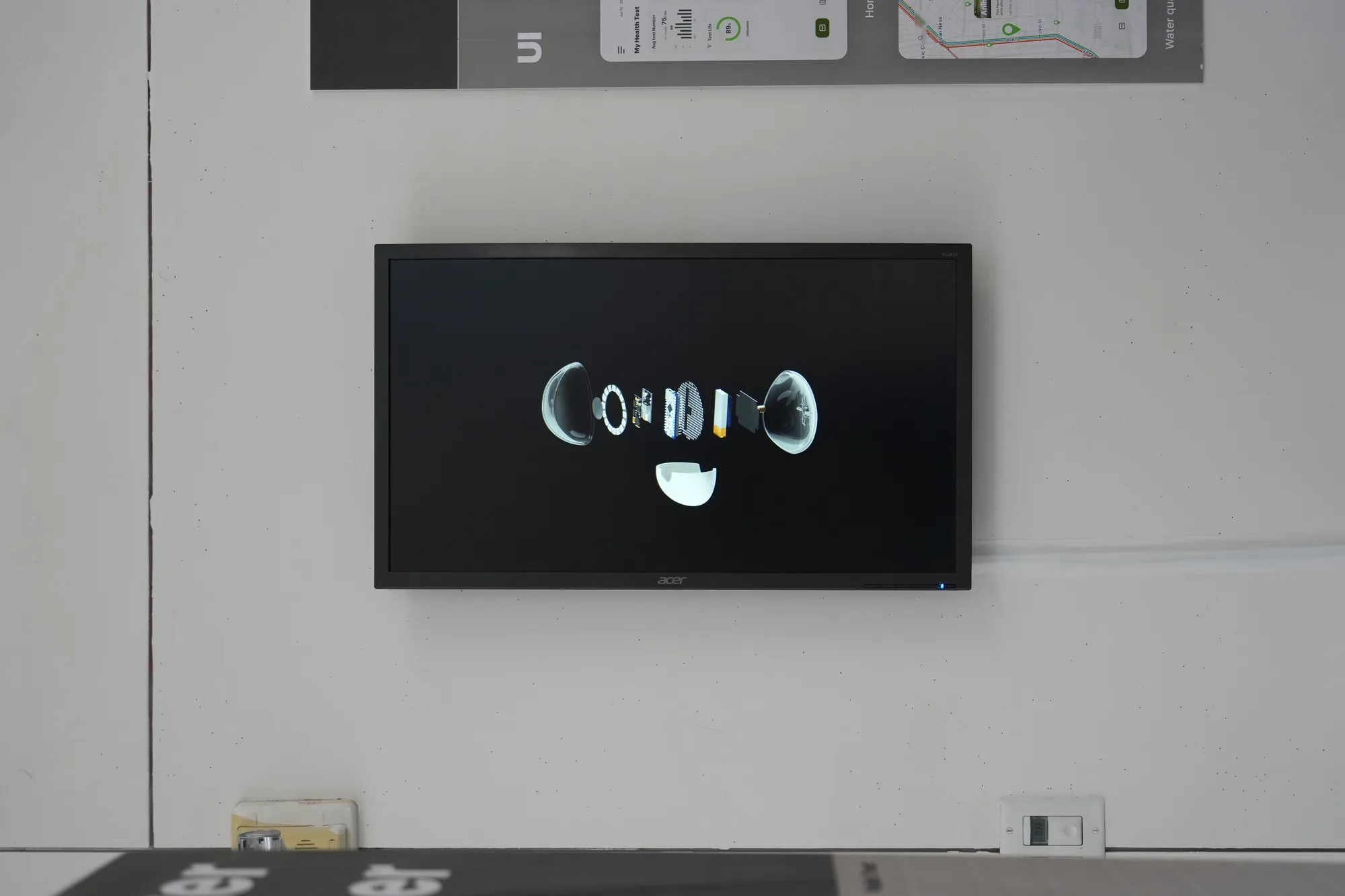 The Pebble exhibition wall: a screen playing the exploded-view render of the device beneath a row of annotated diagrams