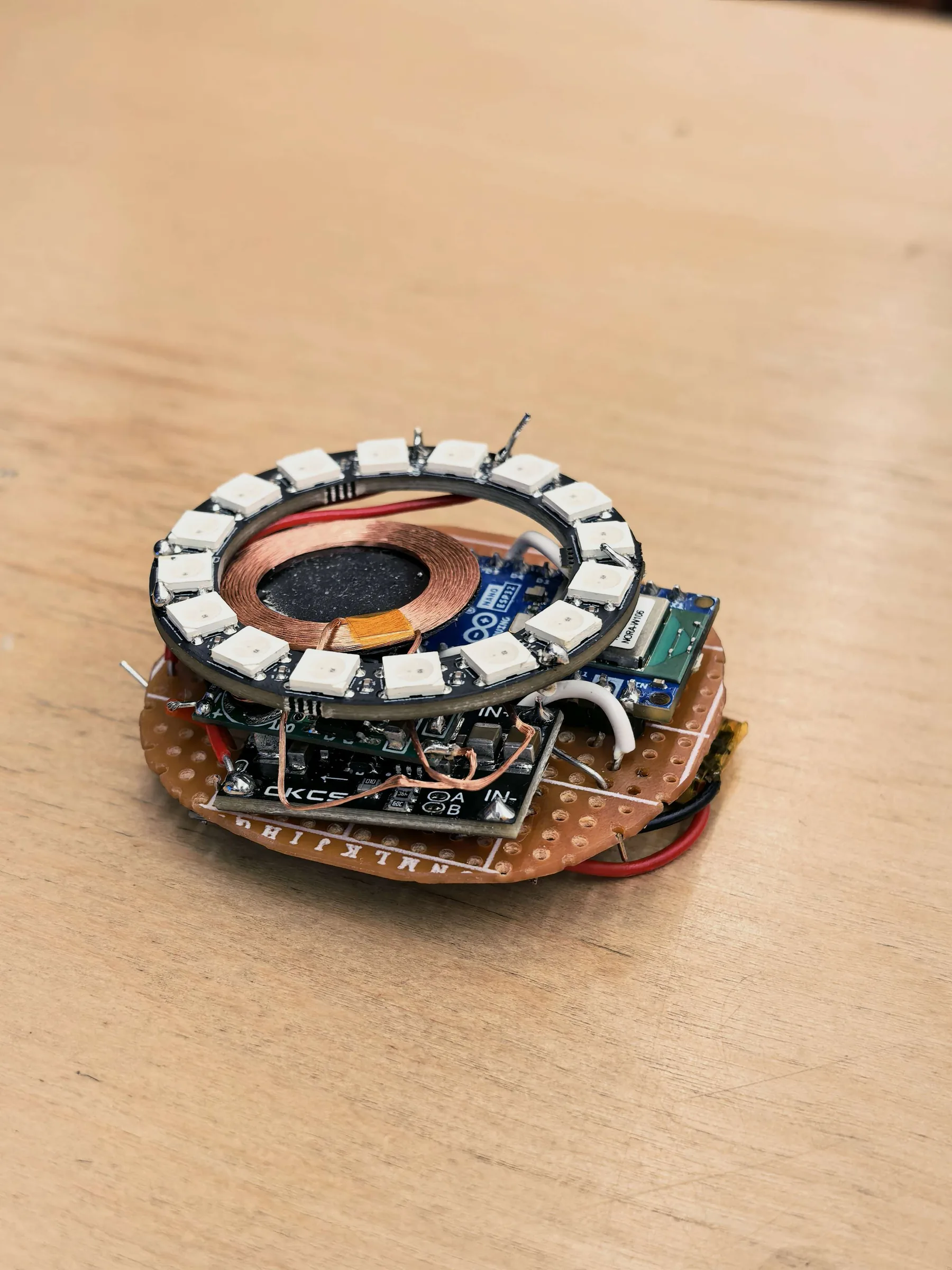 The Pebble engineering prototype: a circular sensing board ringed with feedback LEDs, resting on a wooden table